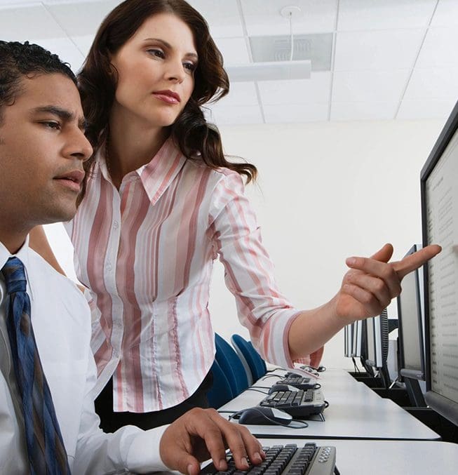 A woman pointing at something on the computer screen.