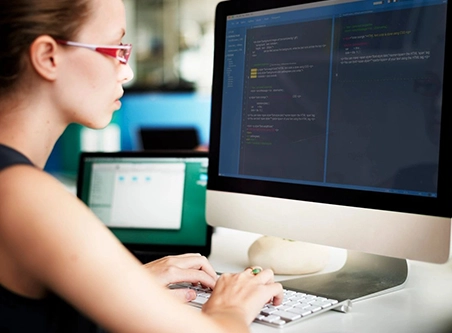 A woman sitting at her computer desk typing.